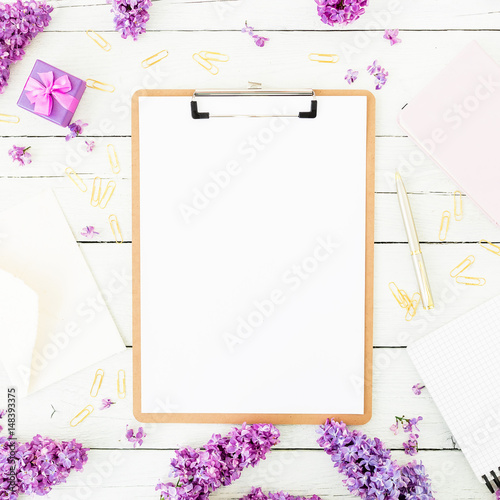 Minimalistic workspace with clipboard, envelope, pen, lilac, box and accessories on wooden background. Flat lay, top view. Beauty blog concept.