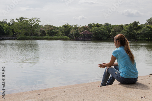 Young Asian woman sit near the Lake. © akelomongkol