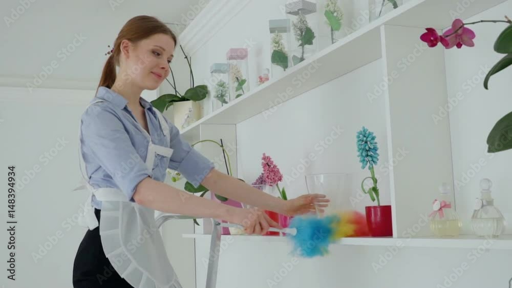 woman with duster cleaning dust from shelf at hotel woman with duster cleaning dust from shelf at hotel