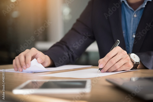 Businessman writing in a document. Focus on the tip of the pen