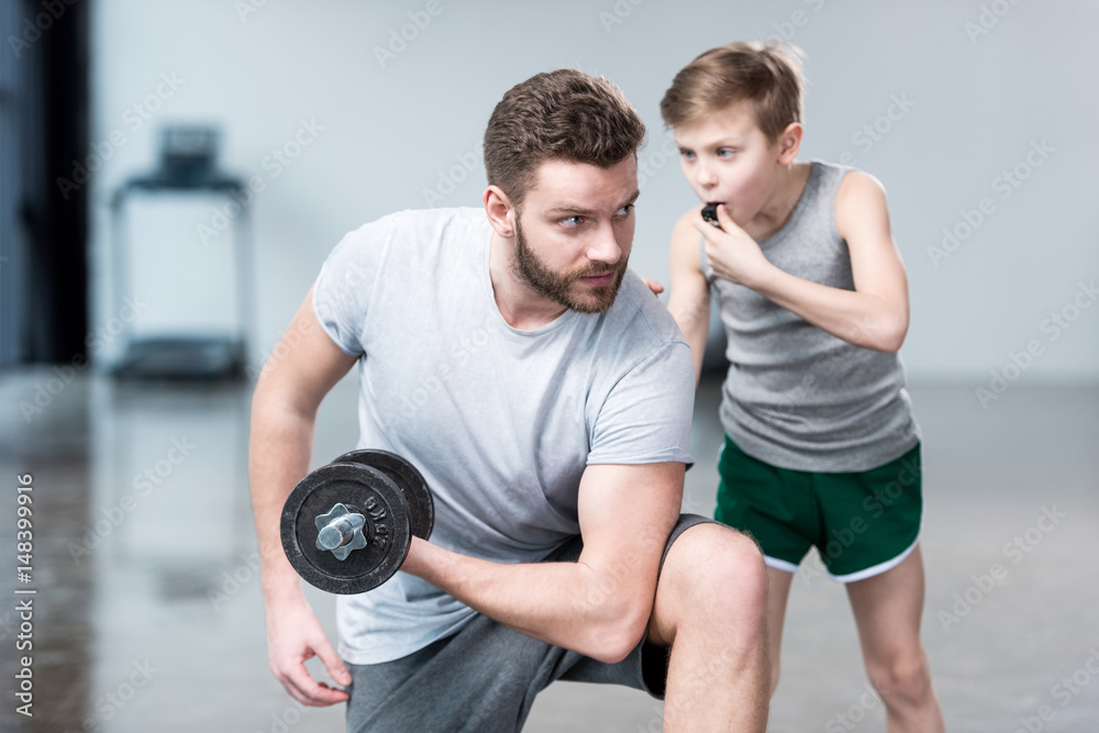 Boy coach training man exercising with dumbbell Boy coach training man exercising with dumbbell