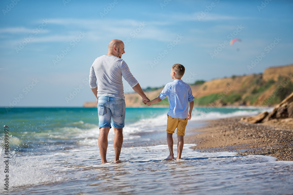 Father and son playing on the beach at the day time. Concept of friendly family. Father and son playing on the beach at the day time. Concept of friendly family.