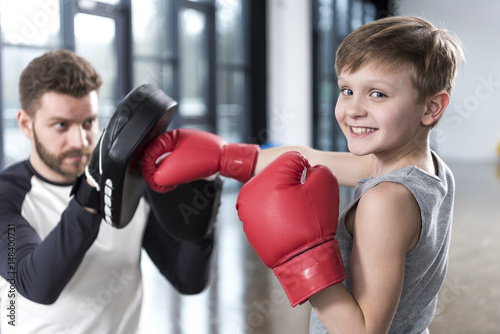 Obraz na plátně young boy boxer practicing punches with coach