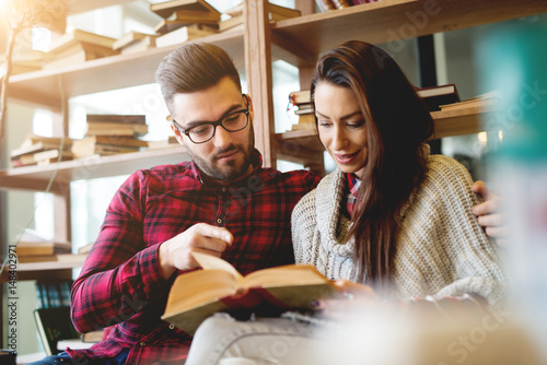 Handsome stylish couple reading book at modern library. © dusanpetkovic1