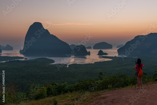 Photographer woman standing outdoor photography amidst the beautiful scenery of mountain view and sea from view Samet Nang She at Phang Nga province in Thailand. travel and natural Concept 