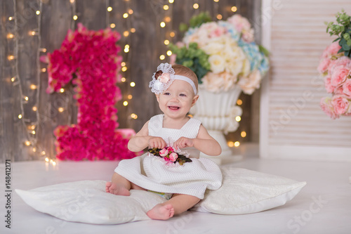 Cute baby girl 1-2 year old sitting on floor with pink balloons in room over white. Isolated. Birthday party. Celebration. Happy birthday baby, Little girl with group ball. Play room.