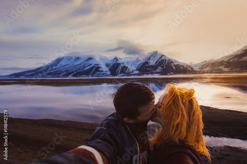 couple red-haired girl and man kissing on the background nature winter snow-capped mountains of Svalbard, Longyearbyen, Spitsbergen, Norway at the time of fire rolled reflection ocean wallpaper