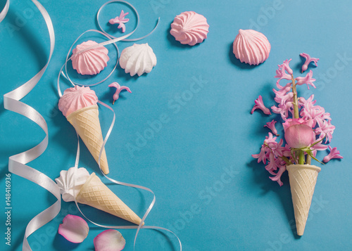 Meringue pie and flowers in a waffle horn on a blue background photo