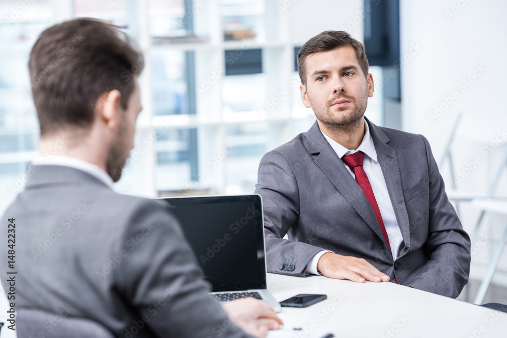Two businessmen in formal wear sitting and talking at job interview, business concept Two businessmen in formal wear sitting and talking at job interview, business concept