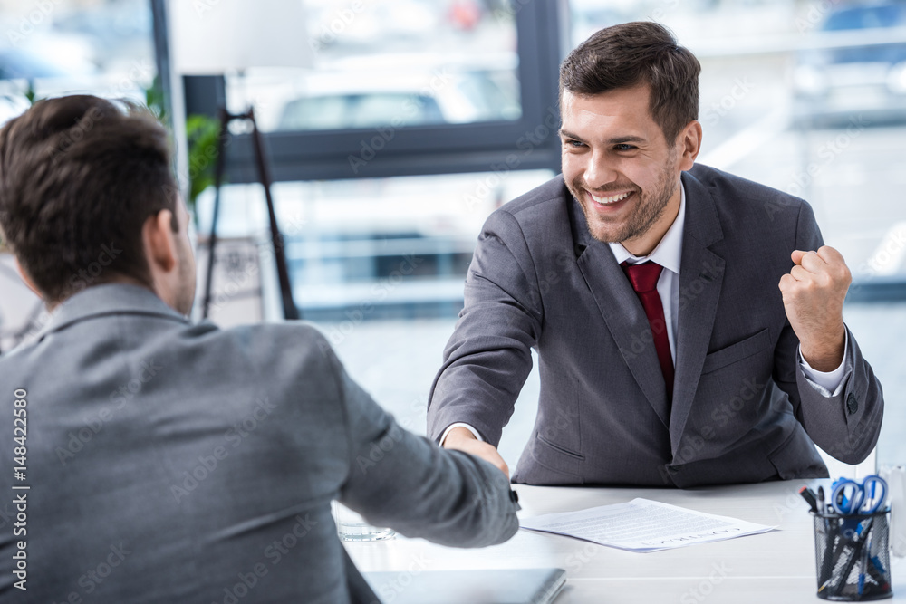 Two smiling businessmen shaking hands at meeting in office, business concept Two smiling businessmen shaking hands at meeting in office, business concept