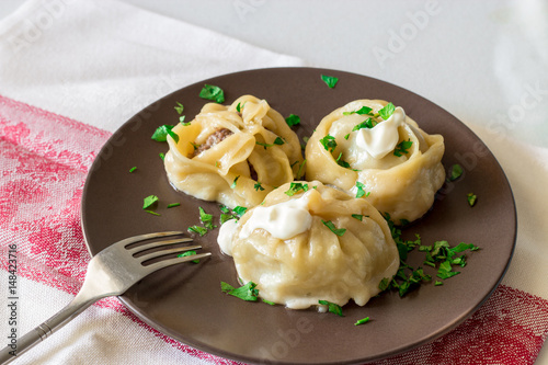 Khinkali, manti, pose, buzi, dumplings - a traditional meat dish of central Asia. On a brown plate. Selective focus photo