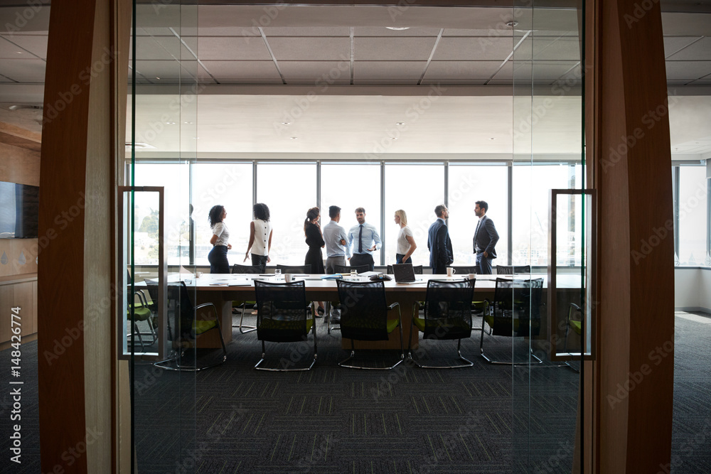 Businesspeople Stand And Chat Before Meeting In Boardroom