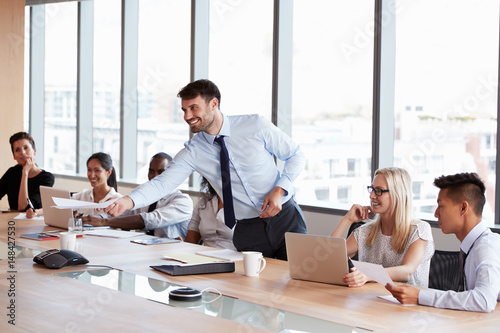 Businessman Stands To Address Meeting Around Board Table