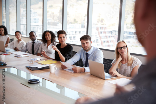 Businessman Stands To Address Meeting Around Board Table