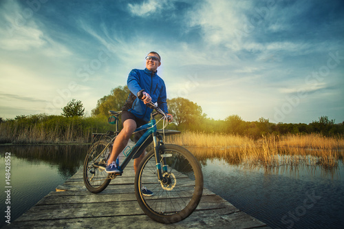 man cyclist Rides on a wooden bridge across the river