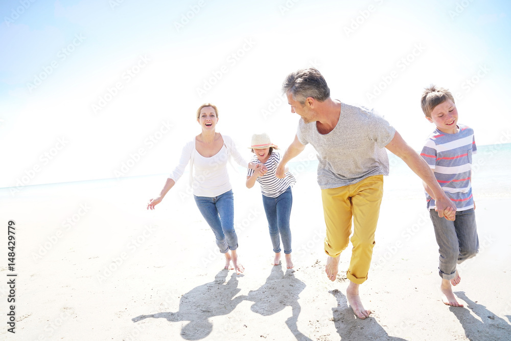 Happy family of four walking on sandy beach