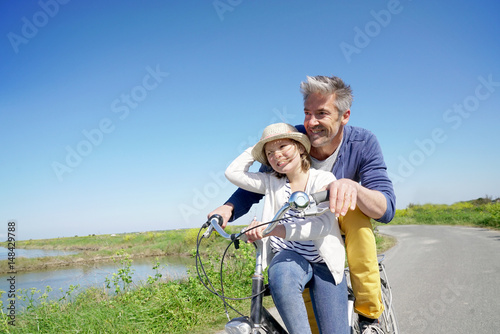 Father and daughter having fun riding bike together
