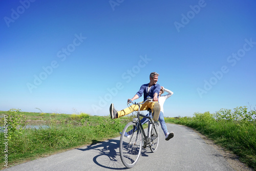Fototapeta Naklejka Na Ścianę i Meble -  Cheerful couple riding bike on a sunny day