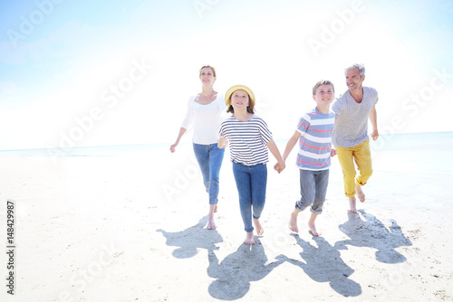 Happy family of four walking on sandy beach