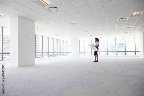 Female Architect In Modern Empty Office Looking At Plans