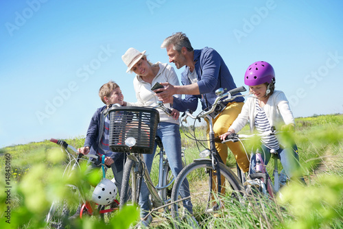 Family on a biking day making a stop and using smartphone