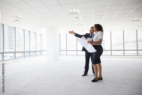 Businesspeople Meeting To Look At Plans In Empty Office