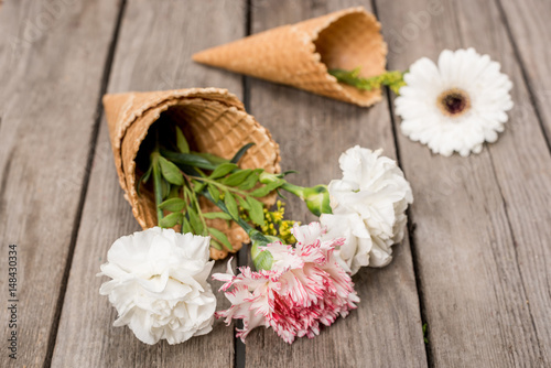 close up of flowers in sugar cones laying on wooden table, wooden background