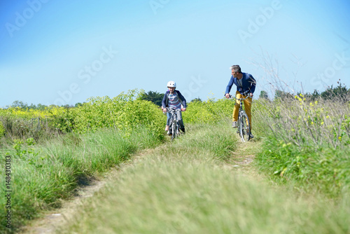 Father with kids riding bicycle in countyside