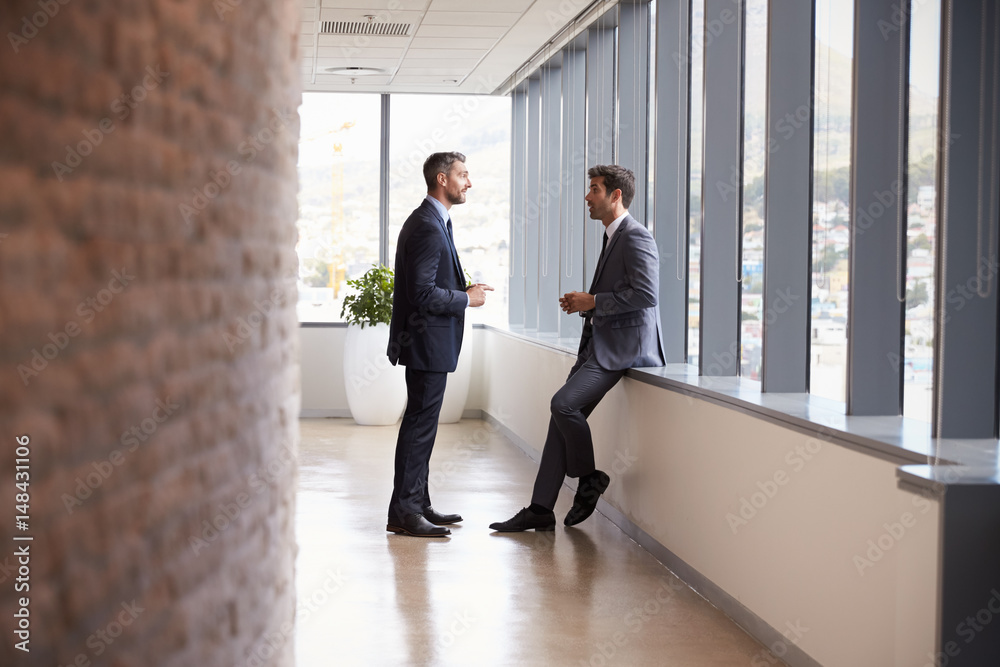 Two Businessmen Having Informal Meeting In Office Corridor Two Businessmen Having Informal Meeting In Office Corridor