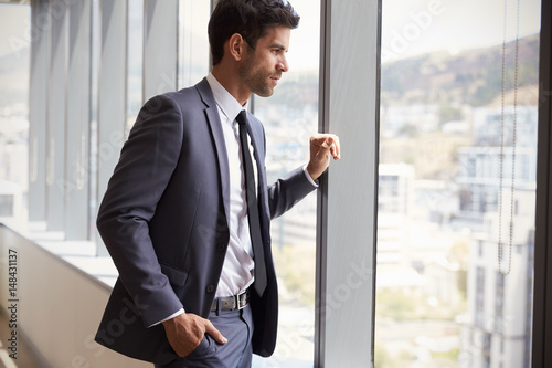 Young Businessman Looking Out Of Window In Office