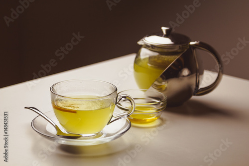 Herbal mint tea in a glass cup with lemon, the teapot and honey