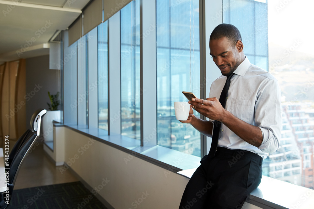 Fototapeta premium Man using phone while sitting on&nbsp;windowsill