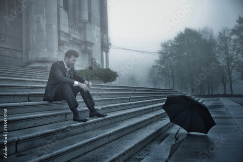 sad man sitting with rose in a foggy day photo