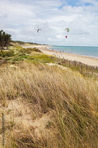 Kite surfing on the deserted Atlantic beach  on the island of Ile de Re with dunes covered with grass in the foreground, France