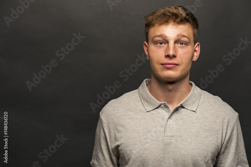 Man in grey polo t-shirt on black background with smile
