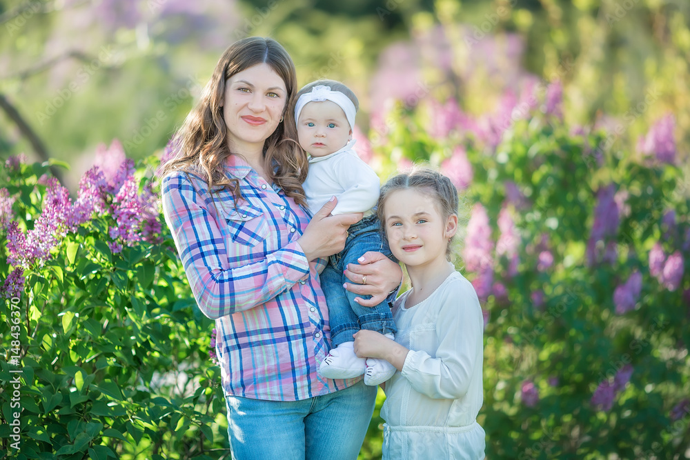 Fototapeta premium happy mother and daughter with green apples in the garden of blooming lilacs