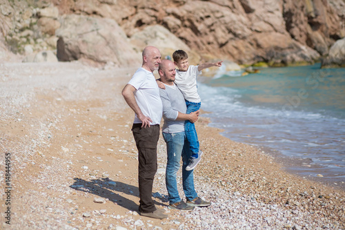 Family of grandfather father and son on a rocky beach on vacation enjoying time together