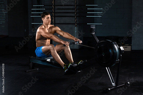 Muscular man doing exercise for legs in the gym