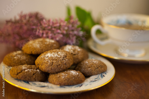 a plate of Molasses cookies with green tea in a vintage porcelain teacup with purple flowers 