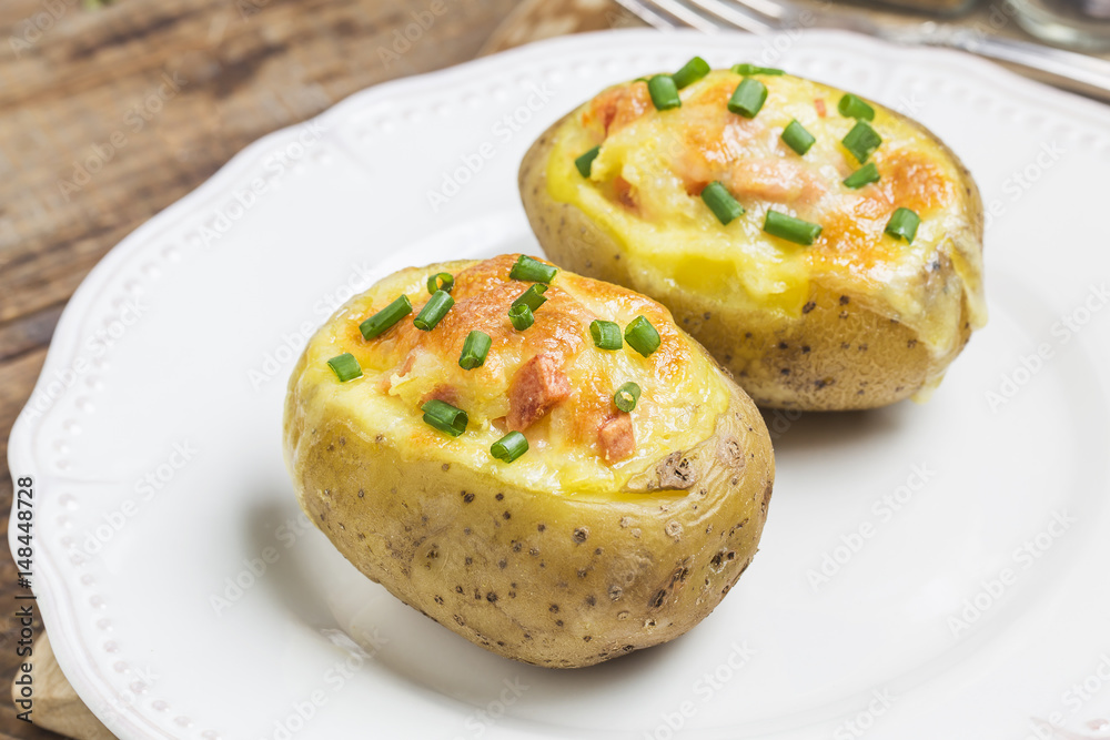 Close up of a hot baked potato topped with sour cream, bacon, green onions and cheddar cheese. Close up of a hot baked potato topped with sour cream, bacon, green onions and cheddar cheese.