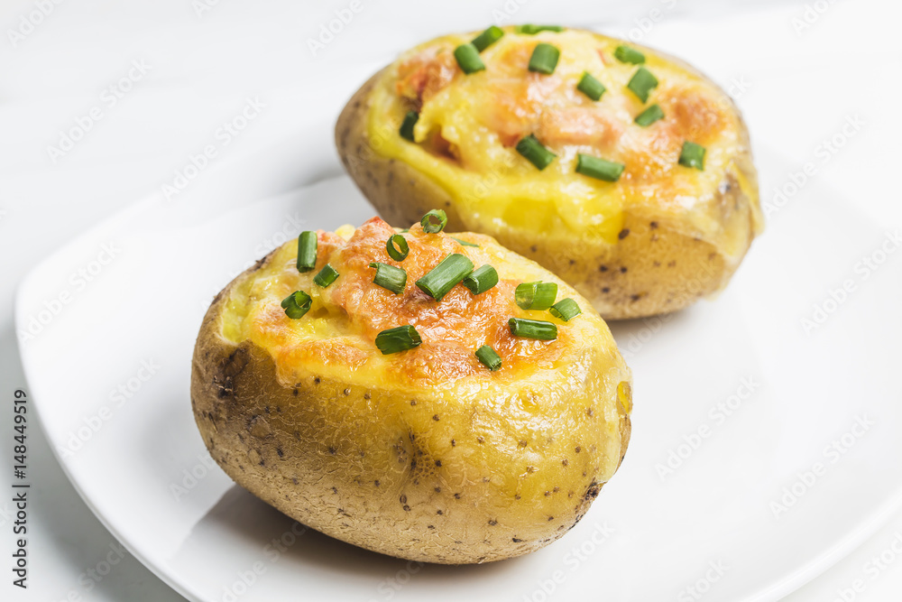 Close up of a hot baked potato topped with sour cream, bacon, green onions and cheddar cheese. Close up of a hot baked potato topped with sour cream, bacon, green onions and cheddar cheese.