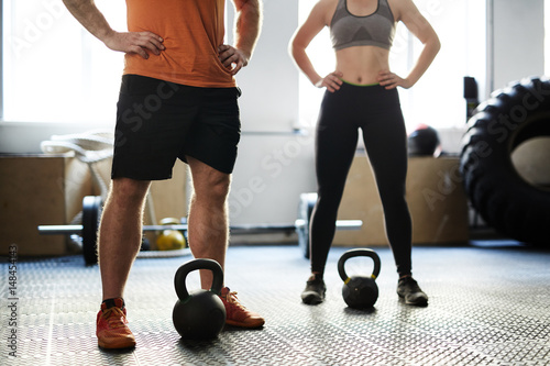 Fototapeta Naklejka Na Ścianę i Meble -  Unrecognizable man and woman having fitness training with kettlebells in gym