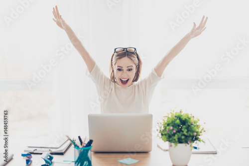 Happy excited successful businesswoman triumphing with laptop photo