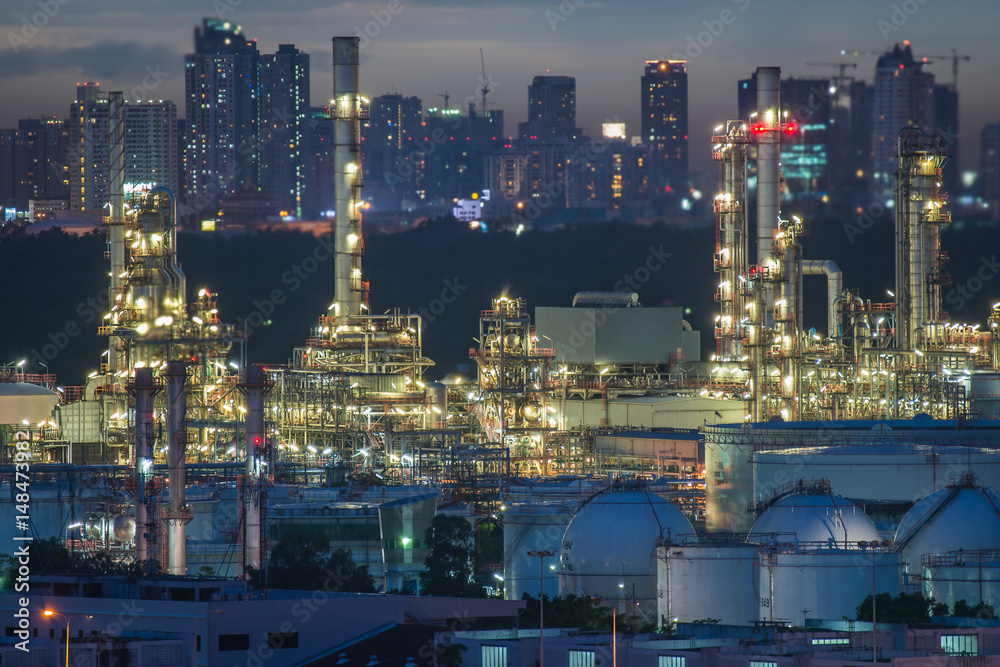 Landscape of oil refinery industry with oil storage tank at night.