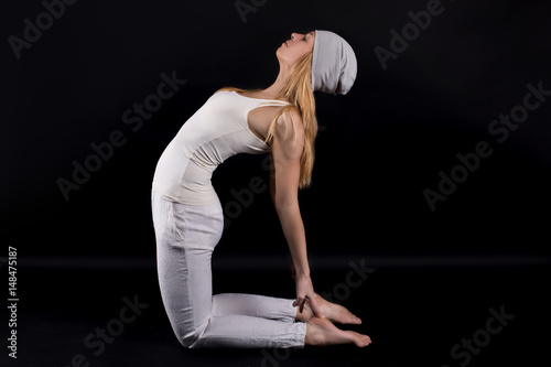 Girl doing yoga exercise in gym isolated on black.