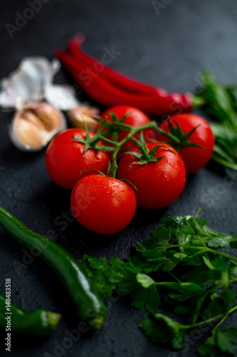 Tomatoes with vegetables on a dark background