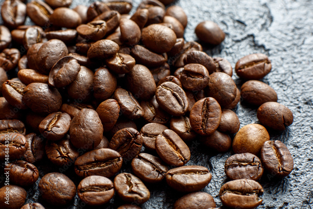 Grains of coffee are scattered on a black stone Grains of coffee are scattered on a black stone
