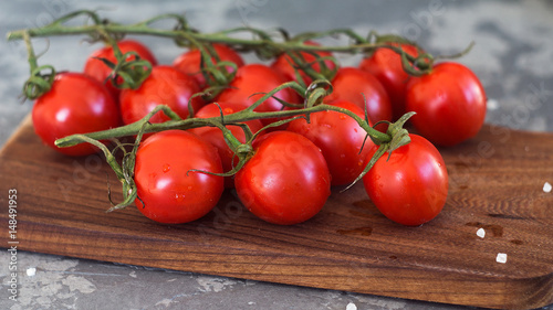 Cherry tomatoes with drops on branch. Wooden background © radiomarlena
