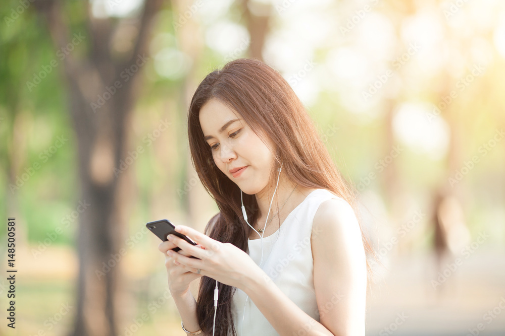 woman using earphone and smartphone at park