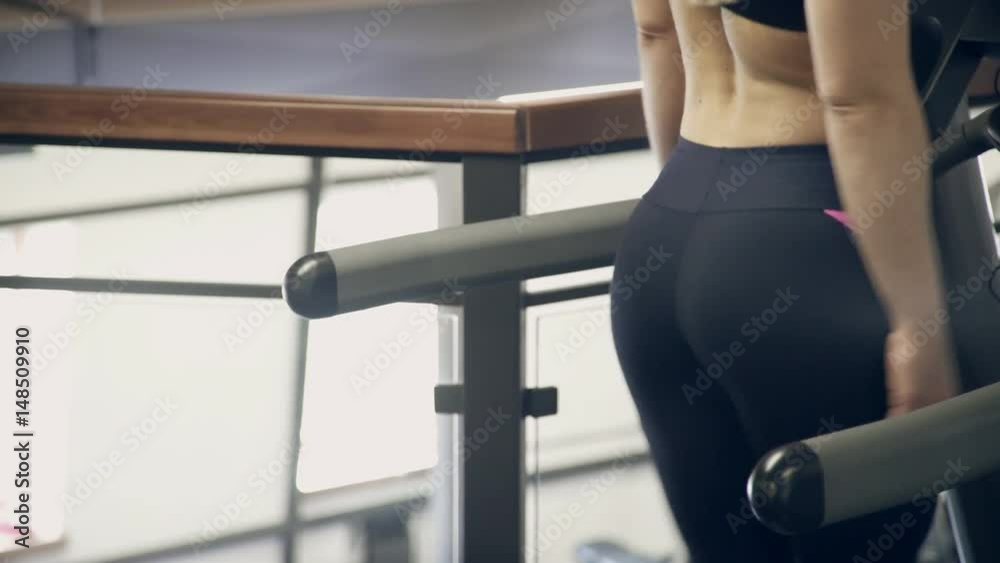 Woman doing exercise Runs on treadmill in fitness studio. Shooting back sportswoman in black violet pants, moving in sports center. Sport female with inflated body shakes legs, booty buttocks dressed Woman doing exercise Runs on treadmill in fitness studio. Shooting back sportswoman in black violet pants, moving in sports center. Sport female with inflated body shakes legs, booty buttocks dressed